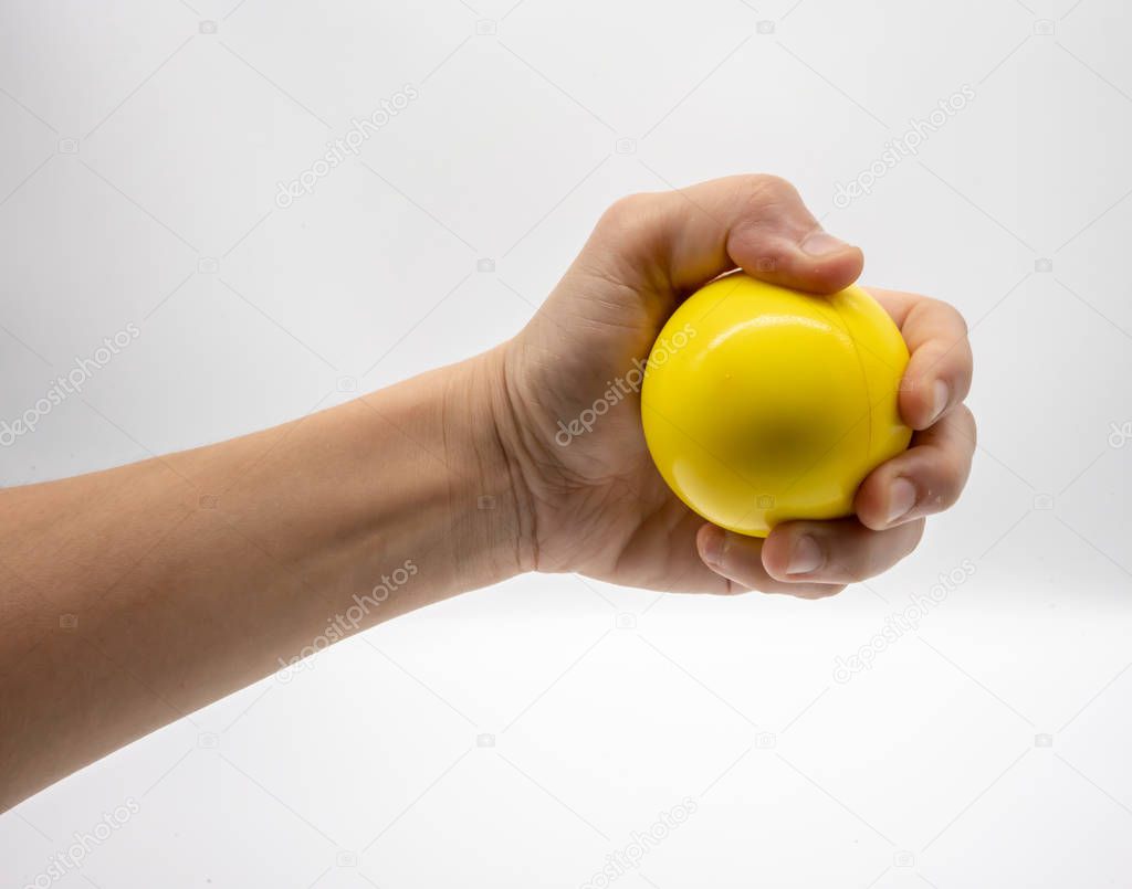 Hand holding yellow stress ball isolated on white background.
