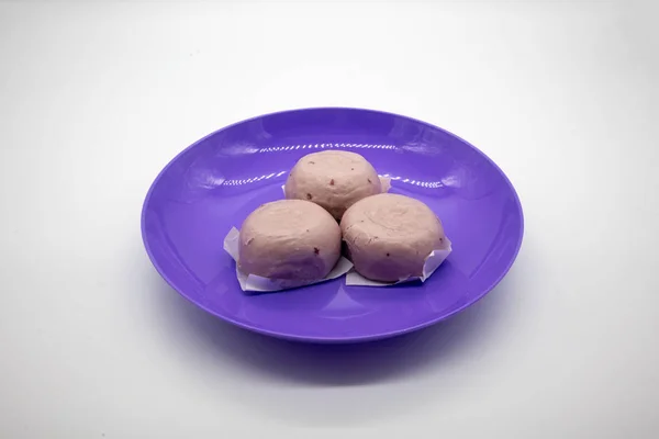 Steamed purple sweet potato Chinese buns on purple plastic plate isolated on white background.