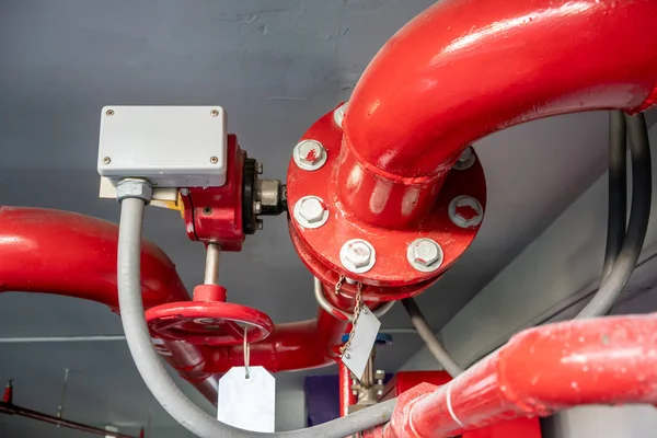 Industrial steel pipes in red L shape on white ceiling background.