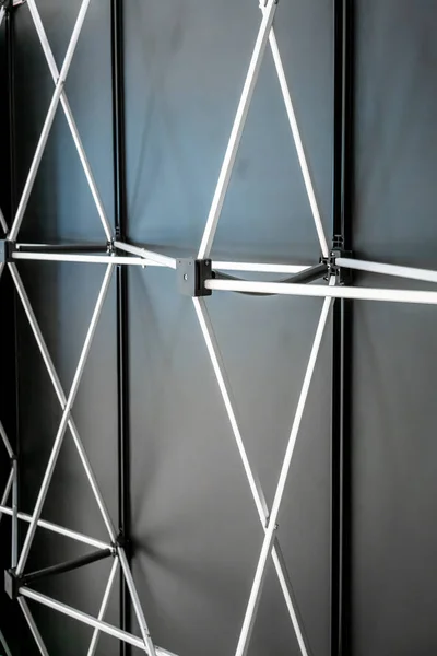 Light steel truss girder element against black background. Backdrop structure.