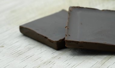 Ahşap arka plan üzerinde kare parça parça bitter çikolata kadar kapatın.