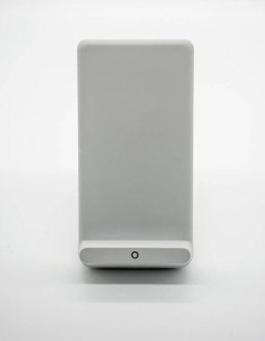 Beyaz arka plan üzerinde izole modern tasarımı ile beyaz kablosuz şarj standı.