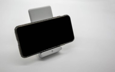 Modern tasarlanmış kablosuz şarj cihazı stand üzerinde beyaz bakcground izole şarj siyah cep telefonu.