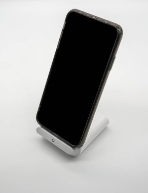 Modern tasarlanmış kablosuz şarj cihazı stand üzerinde beyaz bakcground izole şarj siyah cep telefonu.