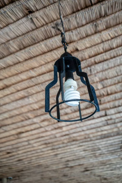 Tavanda asılı beyaz ampul ile siyah metal lamba.