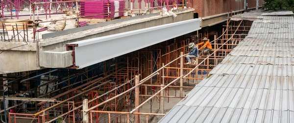 Construction site by public transportation area with two workers.