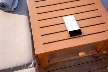 Yan ahşap masa arka planda havuz alanı tahtada beyaz plastik menü.