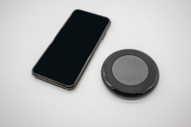Siyah beyaz arka plan üzerinde izole şekil radyo fiyat istemek yuvarlak tarafından yerleştirilen siyah cep telefonu.