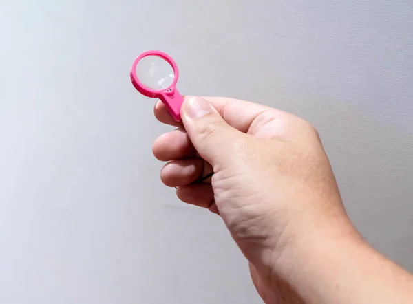 Mano Sosteniendo Pequeña Lupa Plástico Rosa Sobre Fondo Blanco — Foto de Stock