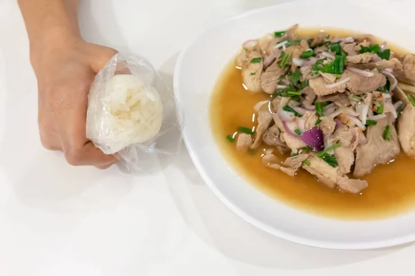Mão segurando arroz pegajoso ao lado de sal de porco picante do nordeste tailandês — Fotografia de Stock