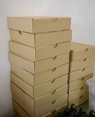 Düz zanaat pizza kutuları beyaz duvar karşı yığını.