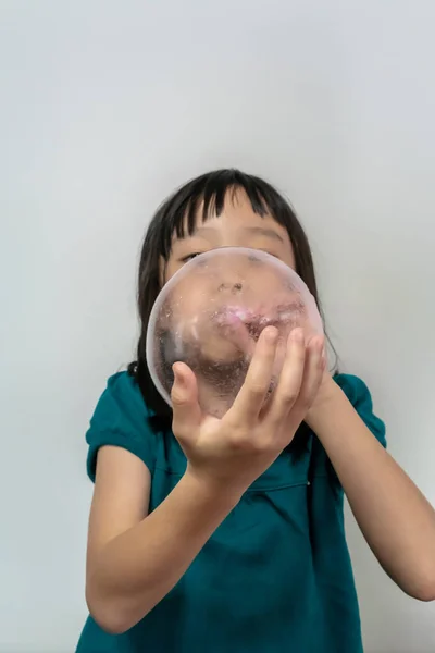 Маленькая девочка надувает розовый воздушный шар с помощью белой пластиковой соломы iso — стоковое фото