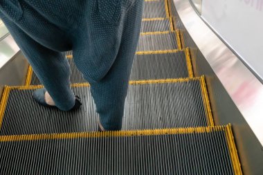 Esca üzerinde duran siyah deri ayakkabılı ve mavi pantolonlu kadın bacağı.