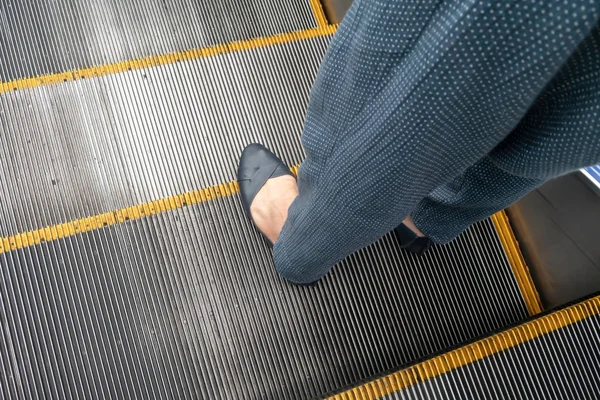 Vrouw been met zwart lederen schoen en blauwe broek staan op esca — Stockfoto