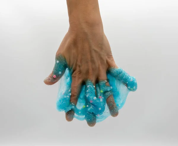 Hand playing or soaking transparent blue glitter slime isolated — Stock Photo, Image