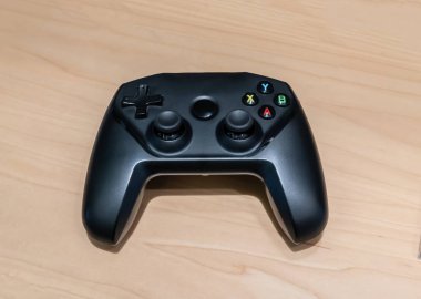 Ahşap masa arkasında kablosuz siyah joystick. 