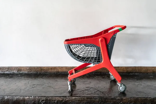 Красный современный дизайн корзины с колесами против белой стены — стоковое фото