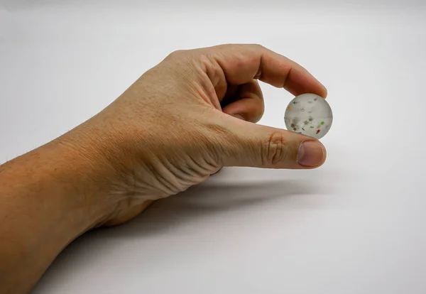 Mano que sostiene la bola de goma transparente con estrellas coloridas dentro — Foto de Stock