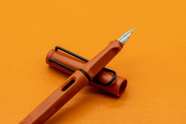 Pluma caligráfica o estilográfica naranja mate sobre fondo naranja —  Fotos de Stock