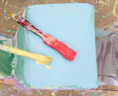 açık mavi arka plan üzerinde kırmızı ve sarı renkli boya fırçası.