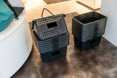 Zemin katta müşterilerin alması için hazır bekleyen siyah plastik sepetler var..