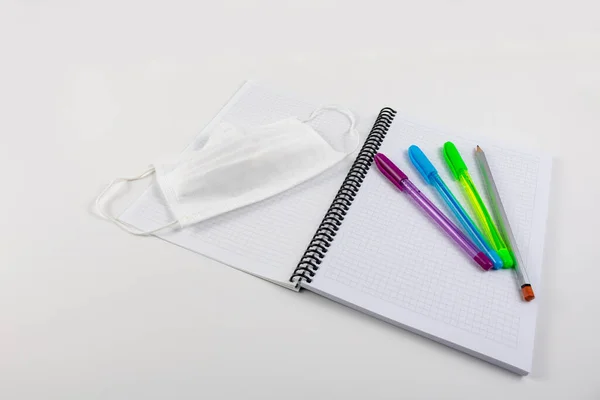 白い背景のノートにコロナウイルスやペンの顔マスクと鉛筆 — ストック写真