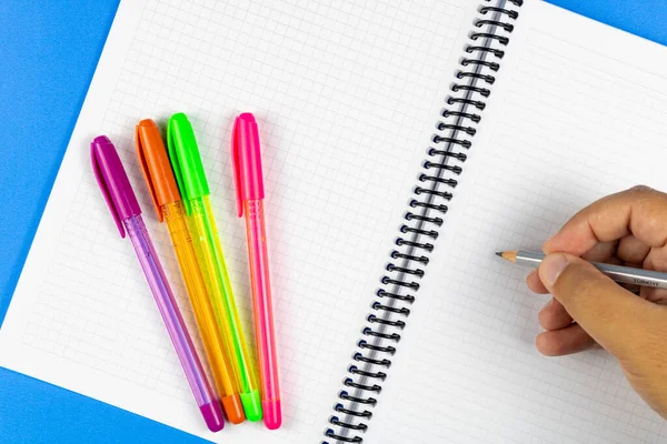 Man Klaar Schrijven Notebook Met Multi Gekleurde Pennen Blauwe Achtergrond — Stockfoto