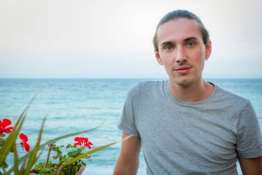 Mavi deniz arka plan üzerinde poz yakışıklı adam manken portresi. Yatay olarak çerçeveli atış.