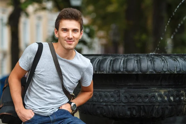 Çeşme arka plan üzerinde genç bir adam portresi. Yatay olarak çerçeveli atış.