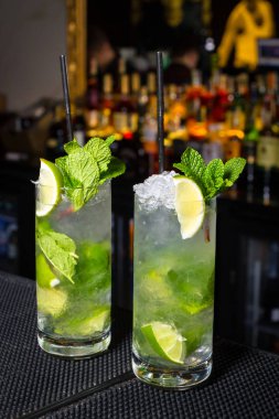İki Mojito kokteyller bir bar şişe ile bulanık arka plan üzerinde counter. Dikey olarak çerçeveli atış.