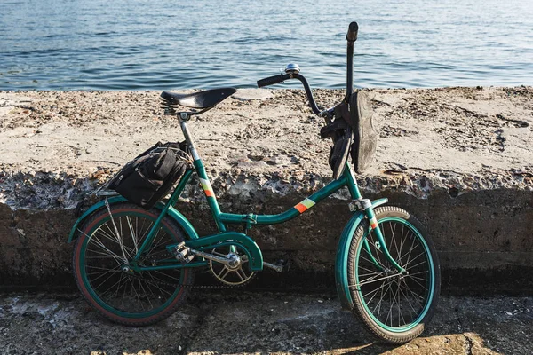 Un vieux vélo se tient sur la jetée par une journée ensoleillée. Contre l'eau de mer . — Photo