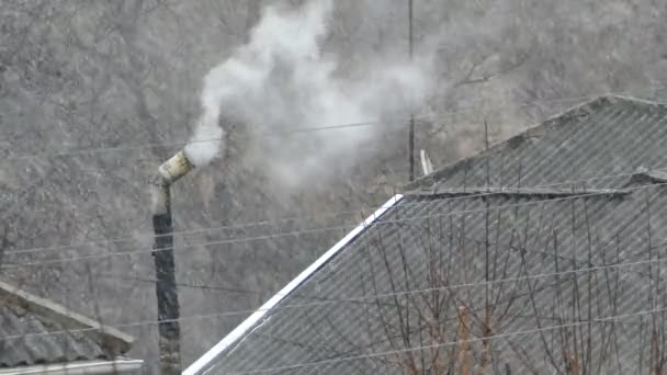在屋顶上吸烟的烟囱和房屋的雪发出浓烟 下雪了 加热季节 2160 25Fps Uhd — 图库视频影像