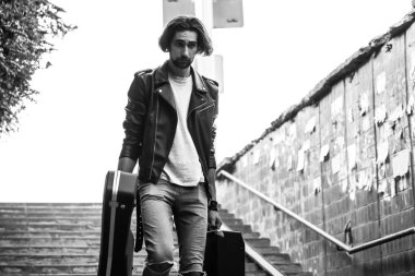 Bir vaka bir gitar ve amfi ile tutarak Sokak müzisyeni. Merdivenlerden aşağı yeraltı geçidi gider. Serseri bir yaşam tarzı. Para kazanmaya oynuyorum. İşsiz müzisyen. Gelecekteki rock yıldızı. Yatay olarak çerçeveli atış.