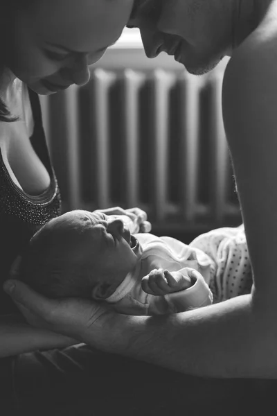 Kadın ve erkek elele üzerinde yeni doğmuş bir bebek. Anne, baba ve bebek. Çocuk çığlıklar ve çığlıkları. Mutlu aile hayatı. Adam doğdu. Arka pencere ve Isıtma pil.