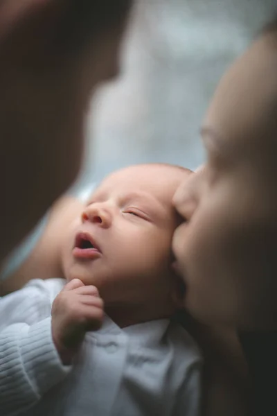 Kobieta i mężczyzna, trzymając w rękach noworodka. Mama, Tata i dziecko. Matka całuje jej syna. Szczęśliwe życie rodzinne. Urodził się człowiek. — Zdjęcie stockowe