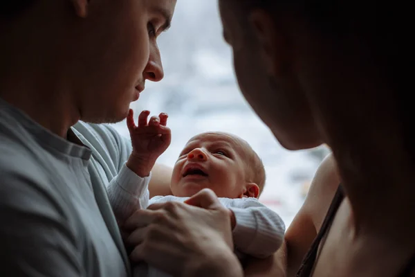 Kadın ve erkek elele üzerinde yeni doğmuş bir bebek. Arka camda. Anne, baba ve bebek. Genç aile portresi. Mutlu aile hayatı. Adam doğdu.