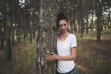 Güzel genç esmer bir çam ormanı içinde.