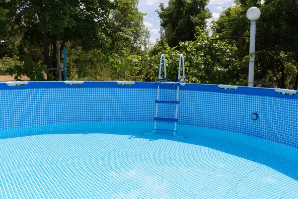 La piscina azul está medio llena de agua . — Foto de Stock