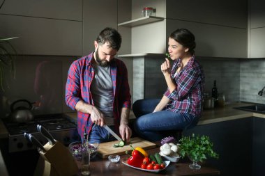 Güzel genç çift mutfakta yemek sağlıklı yemek sırasında evde. Kesim salata adamdır. Kadın tablo ve maydanoz yemek oturur. Olay yerinden aile hayatı.