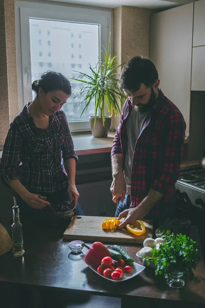 Güzel genç çift mutfakta yemek sağlıklı yemek sırasında evde. Koca bir biber keser. Karısı karışımı salata. Olay yerinden aile hayatı. — Stok fotoğraf