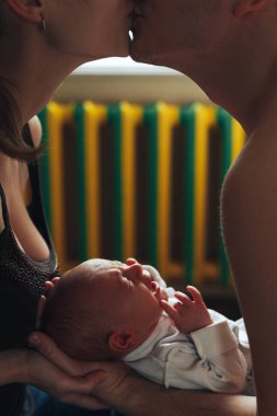 Kadın ve erkek elele üzerinde yeni doğmuş bir bebek. Anne, baba ve bebek. Anne öpücüğü. Çocuk çığlıklar ve çığlıkları. Mutlu aile hayatı. Adam doğdu. Arka pencere ve Isıtma pil.