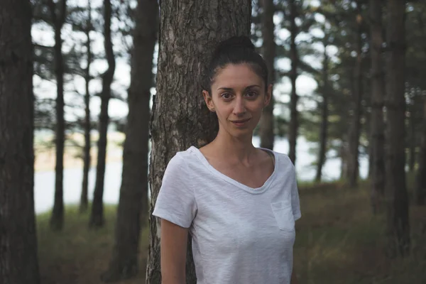 Güzel genç esmer bir çam ormanı içinde.
