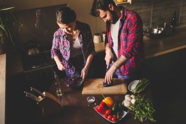 Güzel genç çift mutfakta yemek sağlıklı yemek sırasında evde. Koca lahana kesti. Karısı karışımı salata. Olay yerinden aile hayatı.