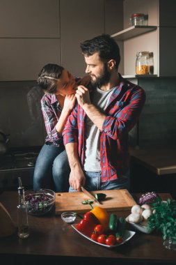 Güzel genç çift mutfakta yemek sağlıklı yemek sırasında evde. Koca salata keser ve eşi salatalık beslenir. Olay yerinden aile hayatı.
