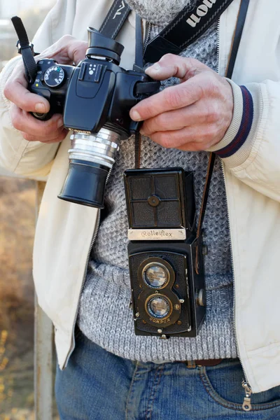 摩尔多瓦共和国基希讷乌 - 2019年3月30日：一名男子摄影师手持复古摄影相机Rolleiflex中等格式双镜头反光相机和现代数码相机Canon. — 图库照片