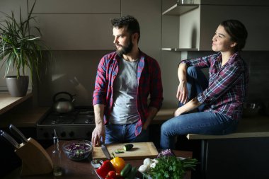 Evde mutfakta güzel genç çift sağlıklı yemek pişirirken. Aile hayatından bir sahne.