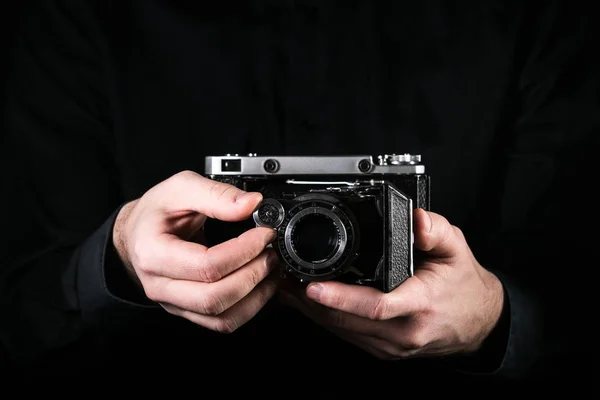 摩尔多瓦共和国基希讷乌 - 2019年3月12日：男子摄影师手持相机。拍摄过程。复古照片相机在黑色背景的中等格式。俄罗斯相机莫斯科 5. — 图库照片