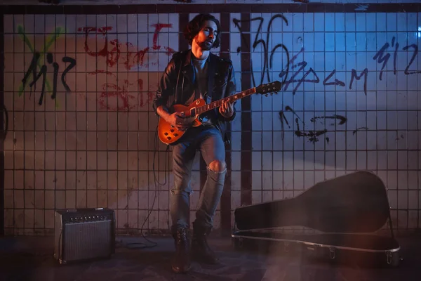 A street musician playing on guitar in the underpass. Vagrant lifestyle. Playing in the underpass to make a living. Unemployed musician. Future rock star.