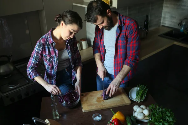 Güzel genç çift mutfakta yemek sağlıklı yemek sırasında evde. Koca lahana kesti. Karısı karışımı salata. Olay yerinden aile hayatı. — Stok fotoğraf