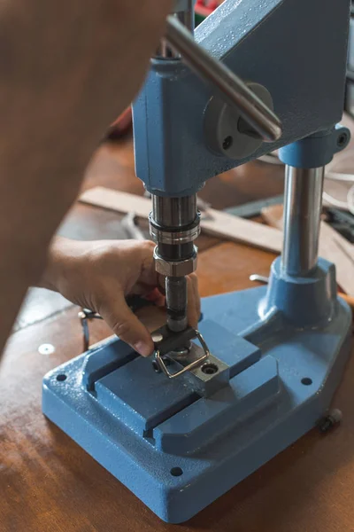 Maître travaille sur la presse avec la peau. Sur une table en bois marron parsemée d'outils et accessoires . — Photo